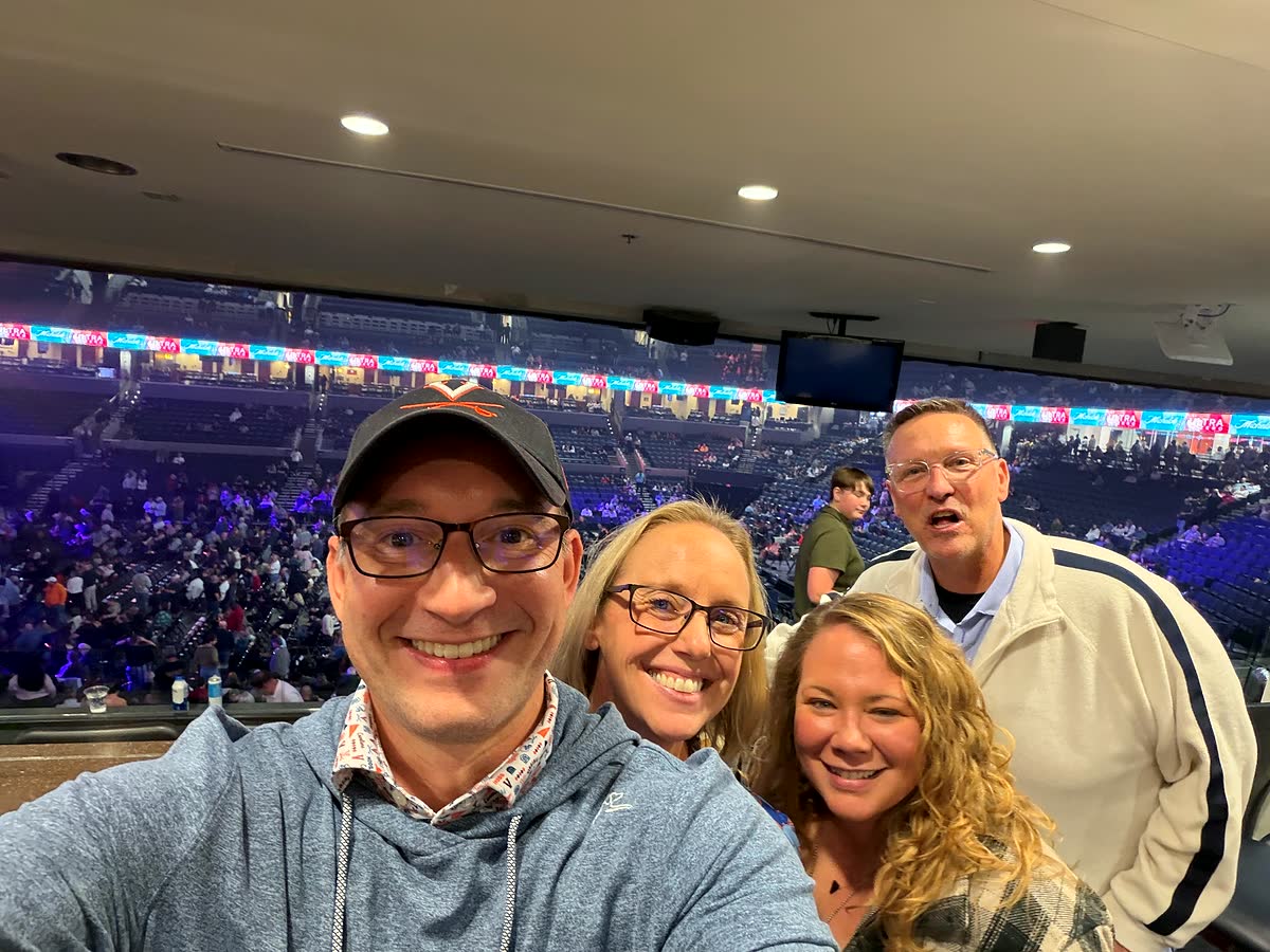 A selfie high in John Paul Jones Arena: Ben, Nicole, Sam and Jason, with the lit-up floor and the crowd far below.