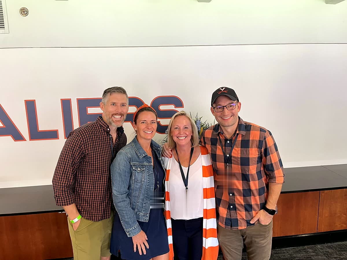 Four of us standing shoulder to shoulder in the president's box, a Cavaliers wordmark painted on the wall behind us.